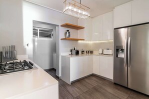 Una cocina moderna con un refrigerador de acero inoxidable, gabinetes blancos y una estufa a gas.