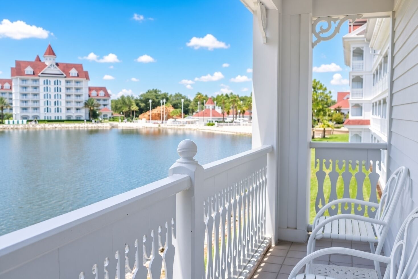 A balcony with white railings overlooking a body of water, with buildings in the background.