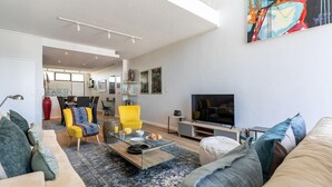 Een moderne woonkamer met een bank, fauteuils, een salontafel en een televisie.