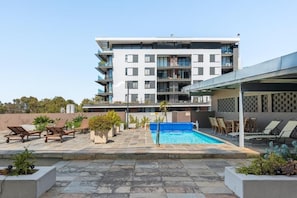 A modern apartment building with a rooftop pool, lounge chairs, and potted plants. - Modern & Artistic, Green Point - Urban Palette Apt (Cape Town)