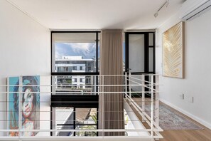 A modern interior with a balcony, a large window, and a painting on the wall. - Modern & Artistic, Green Point - Urban Palette Apt (Cape Town)