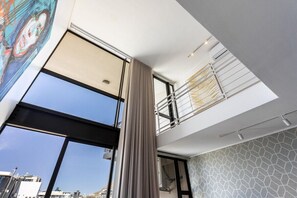 A modern interior with large windows, a balcony, and a geometric patterned wall. - Modern & Artistic, Green Point - Urban Palette Apt (Cape Town)