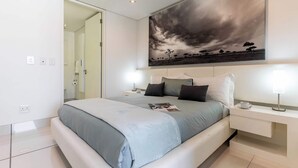 A modern bedroom with a large bed, bedside tables, and a painting of a cloudy sky. - Views, De Waterkant CPT, Communal Pool -901 Mirage (Cape Town)