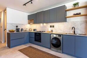 A modern kitchen with grey cabinets, a built-in oven, a washing machine, and a marble backsplash. - Modern, Gorgeous Views, Bo-Kaap - Vista Luxe Apt (Cape Town)