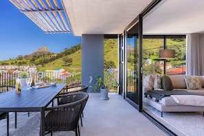 A balcony with a dining table, chairs, and a sofa. - Modern, Gorgeous Views, Bo-Kaap - Vista Luxe Apt (Cape Town)