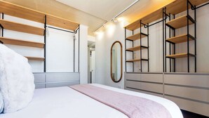 Ein modernes Schlafzimmer mit einem Bett, einem großen Spiegel und eingebauten Regalen mit einer Leiter.