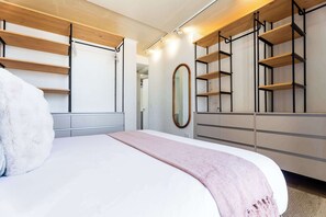 Ein modernes Schlafzimmer mit einem Bett, einem großen Spiegel und eingebauten Regalen mit einer Leiter.