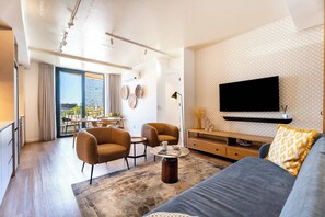 Uma sala de estar moderna com um sofá, duas poltronas, uma mesa de centro e uma TV fixada na parede.