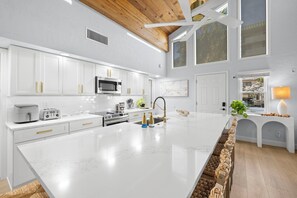 A modern kitchen with white cabinetry, a large island, and a wooden ceiling. - High-end Beach heaven, Sleeps 10, 3 private decks (Indian Rocks Beach)
