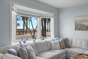 A living room with a large window, a beige sofa, and decorative items on the windowsill. - High-end Beach heaven, Sleeps 10, 3 private decks (Indian Rocks Beach)