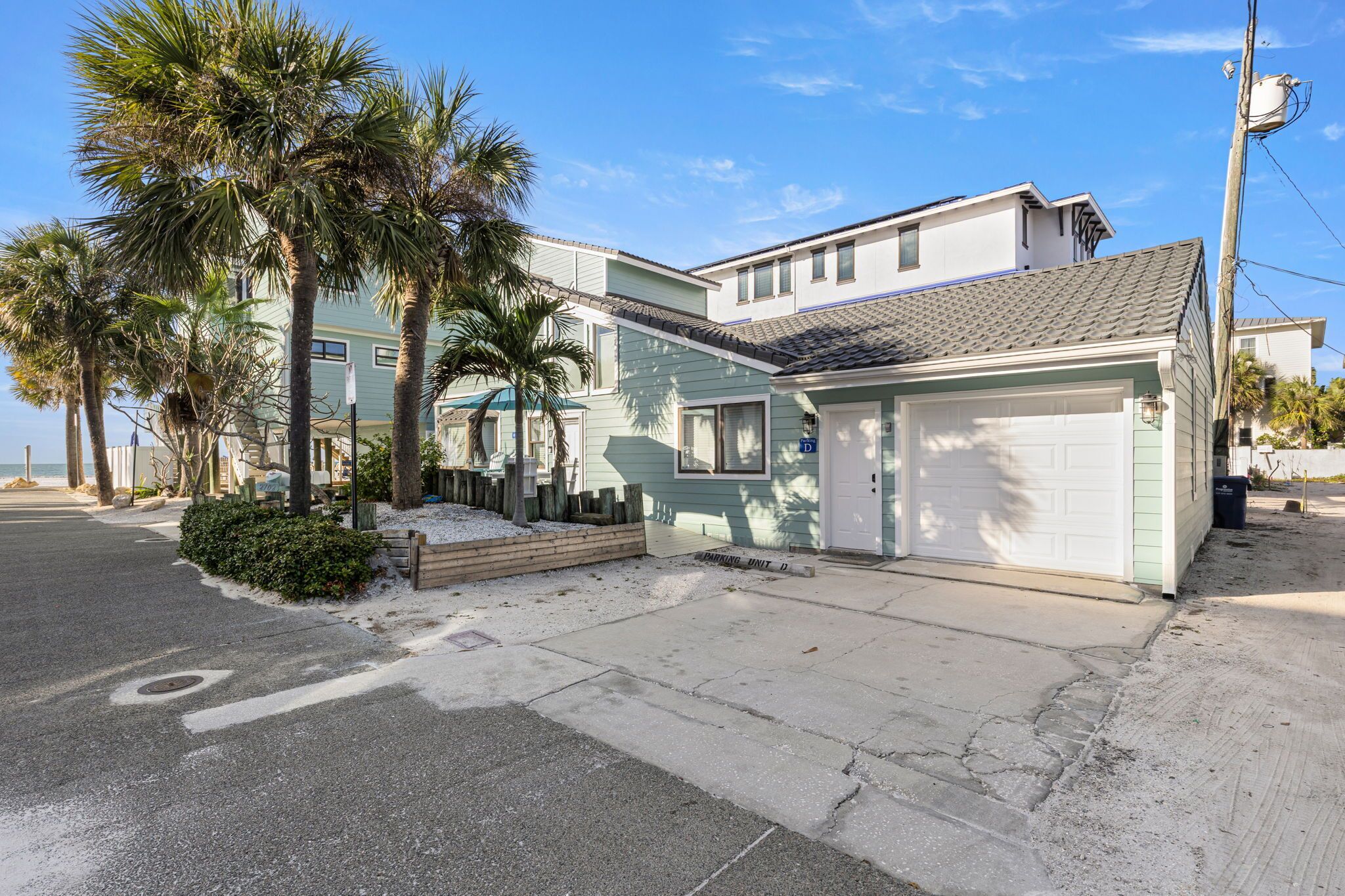 A beachfront property with a two-story building, a garage, and a paved driveway.