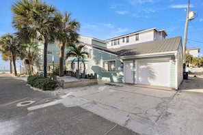 A beachfront property with a two-story building, a garage, and a paved driveway.