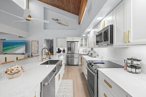 Een moderne keuken met witte kastjes, roestvrijstalen apparatuur en een houten plafond.