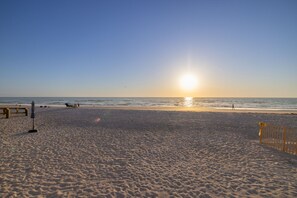 Ein Strand mit einer Holzbank und einem gelben Zaun.