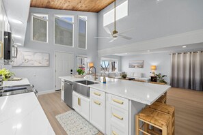 Eine moderne Küche mit weißen Schränken, einer großen Kochinsel und einem Deckenventilator.