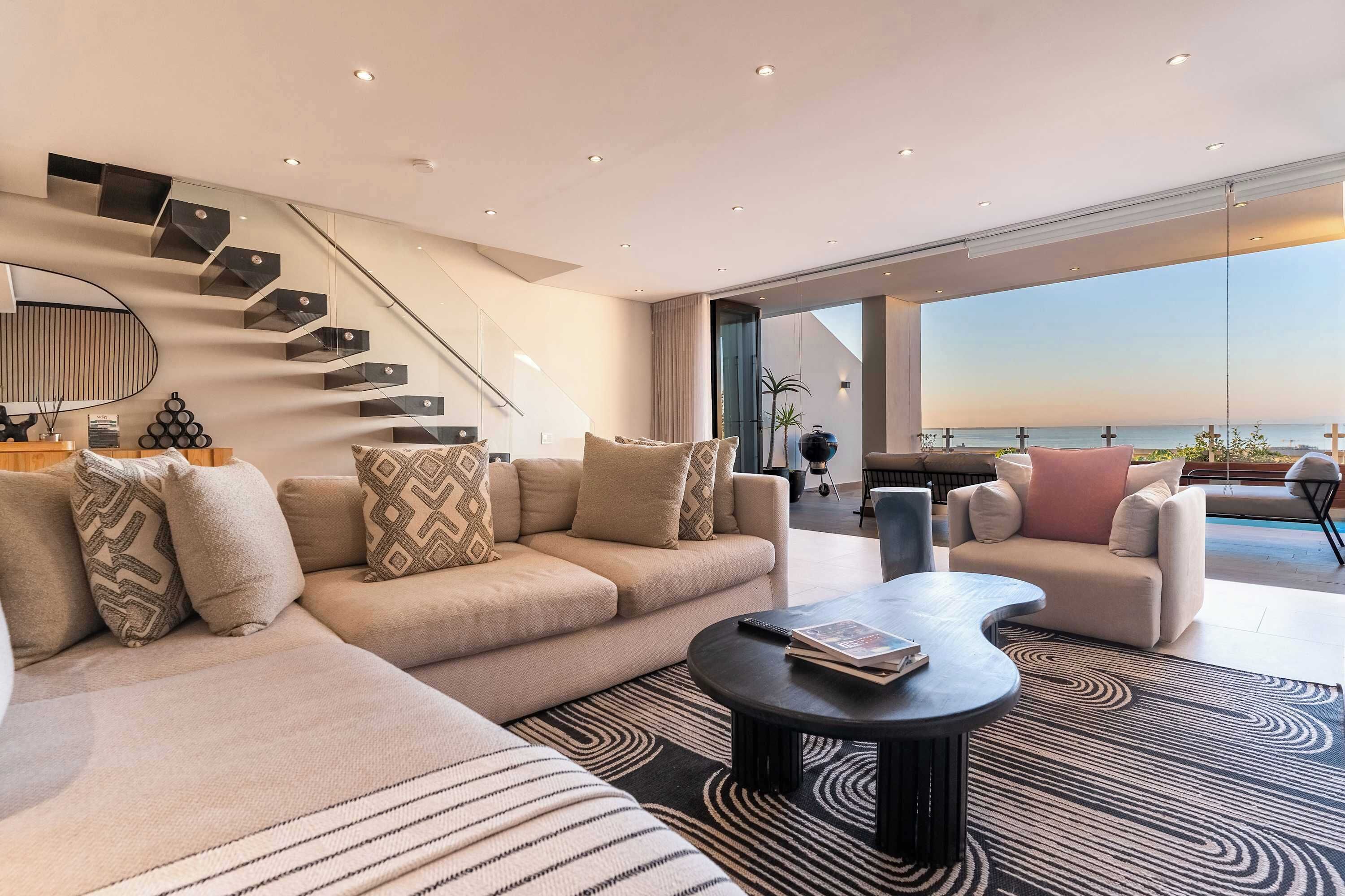 A modern living room with a sofa, coffee table, and a staircase with built-in shelves.
