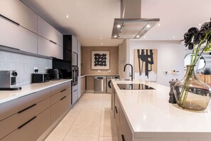 A modern kitchen with built-in appliances, a large island, and a central island sink. - Sea Views, Luxurious, Pool -Iconic View Green Point (Cape Town)