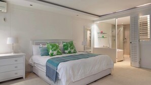 Um quarto moderno com uma cama grande, mesas de cabeceira, um criado-mudo, um espelho e um closet espaçoso.