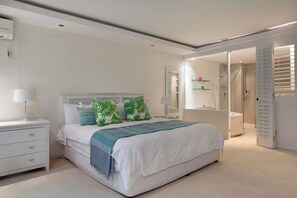 Ein modernes Schlafzimmer mit einem großen Bett, Nachttischen, einem Schminktisch und einem begehbaren Kleiderschrank.