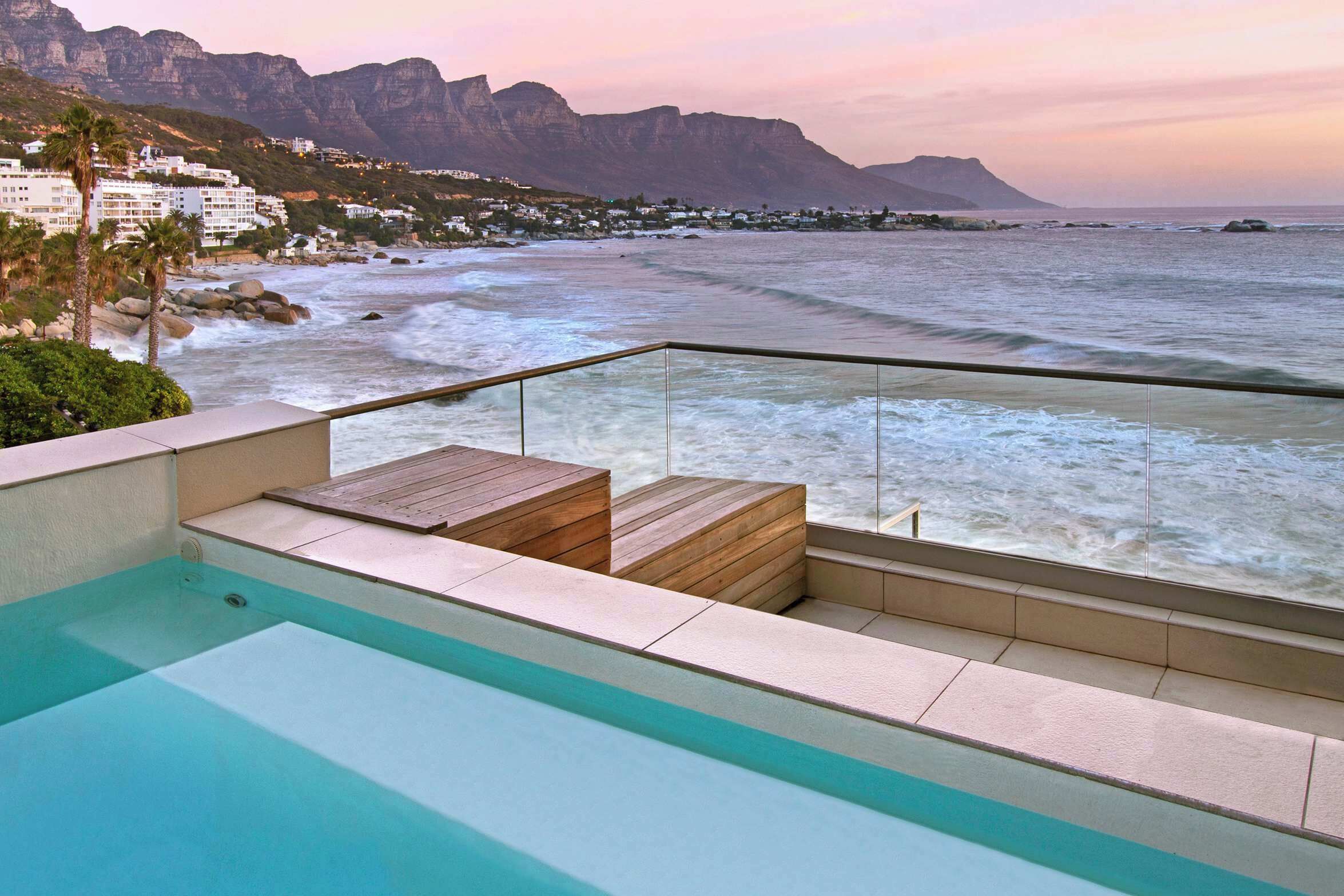A modern outdoor swimming pool with a view of the ocean and mountains.