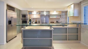Uma cozinha moderna com ilha central, eletrodomésticos embutidos e armários com portas de vidro.