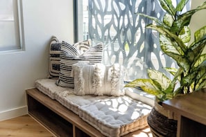 A cozy seating area with a cushioned bench, patterned pillows, and a potted plant. - Luxury, City & Sea Views, Sea Point - Diamond Views Apt (Cape Town)