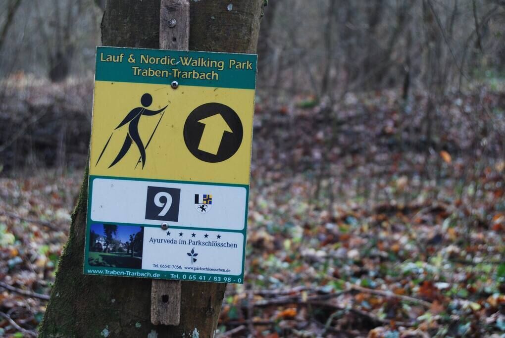 A sign for Lauf & Nordic Walking Park Traben-Trarbach with a walking figure and an arrow.