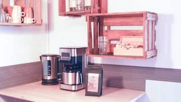 Un comptoir de cuisine avec une machine à café, une bouilloire et un paquet de café.