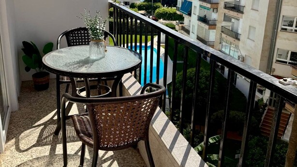 A balcony with a round table and wicker chairs, overlooking a residential area with a clear view of the sea. - Nerja Beachfront Apartment Sea Views and Balcony (Torrijos)