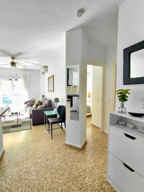 A modern living room with a sofa, chairs, a dining table, and a kitchen in the background.