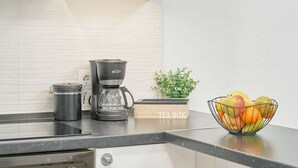 A kitchen with a coffee maker, a tea box, and a fruit bowl on the counter. - Nerja Beachfront Apartment Sea Views and Balcony (Torrijos)