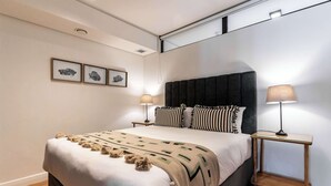 A modern bedroom with a large bed, two bedside tables with lamps, and three framed pictures on the wall. - 270 Views, Modern, Bo-Kaap -Table Mountain Majesty Apt (Cape Town)