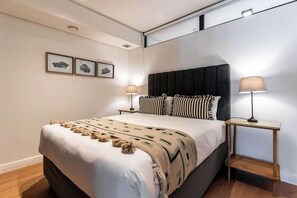 A modern bedroom with a large bed, two bedside tables with lamps, and three framed pictures on the wall. - 270 Views, Modern, Bo-Kaap -Table Mountain Majesty Apt (Cape Town)