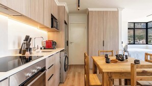 Una cocina moderna con armarios de madera, electrodomésticos de acero inoxidable y una zona de comedor con una mesa y sillas de madera.