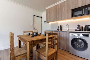 Una cocina funcional con muebles de madera, lavadora y microondas.