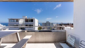 A balcony with a view of the sea, a modern building, and a chair. - Perfect Location, Views - Bantry Bay Pearl Apt (Cape Town)