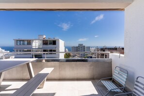 Ein Balkon mit Meerblick, ein modernes Gebäude und ein Stuhl.
