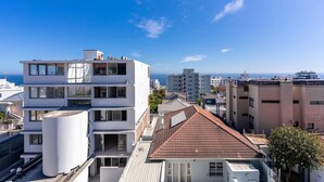 A multi-story building with a flat roof and large windows, surrounded by other buildings and a clear sky. - Perfect Location, Views - Bantry Bay Pearl Apt (Cape Town)