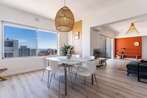 Een moderne woonruimte met een eethoek, grote ramen en uitzicht op de skyline.