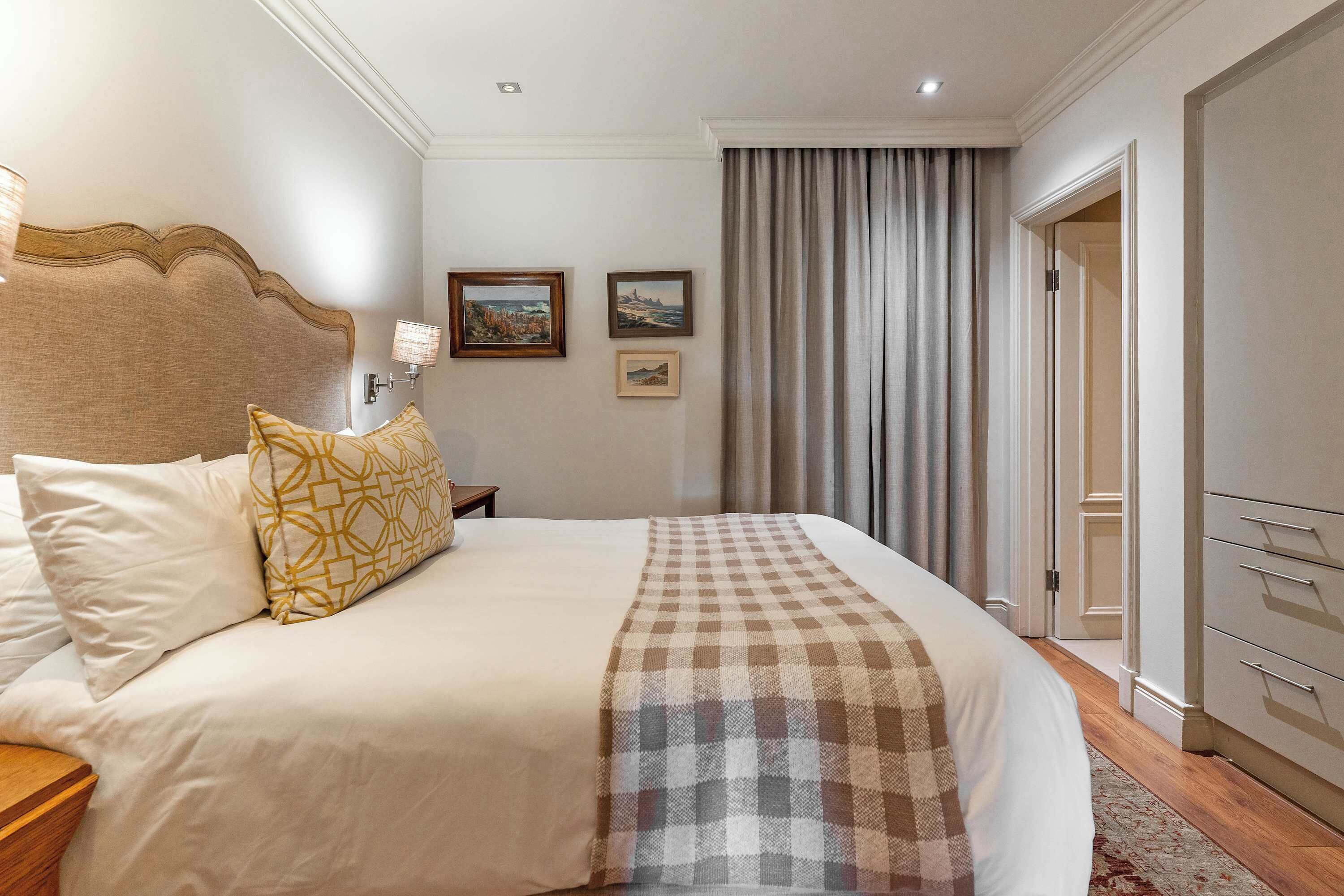 A hotel room with a large bed, a wooden headboard, a nightstand, and a wardrobe.