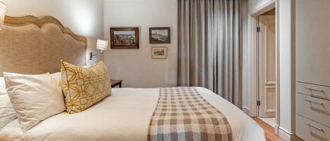 A hotel room with a large bed, a wooden headboard, a nightstand, and a wardrobe.