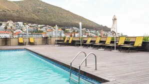 A swimming pool with lounge chairs and a view of a hillside town. - Location, View, Pool, Green Point - Royale 203 Apt (Cape Town)
