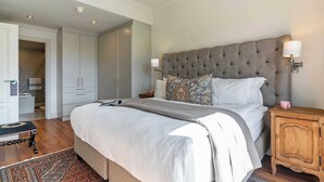 A bedroom with a large bed, a wooden nightstand, a patterned rug, and a wardrobe. - Location, View, Pool, Green Point - Royale 203 Apt (Cape Town)