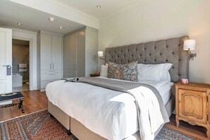 Ein Schlafzimmer mit einem großen Bett, einem Nachttisch aus Holz, einem gemusterten Teppich und einem Kleiderschrank.