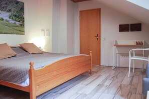 A bedroom with a wooden bed, a desk, and a chair. - Spacious room, private retro bathroom spring water (Traben-Trarbach)