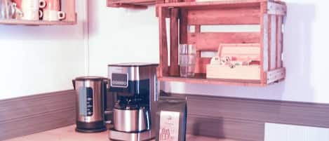 Una encimera de cocina con cafetera, hervidor y una bolsa de café.