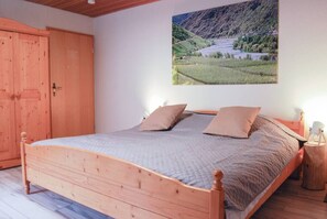 A wooden bed in a room with a large window, a wooden wardrobe, and a wall-mounted picture of a landscape. - Spacious room, private retro bathroom spring water (Traben-Trarbach)
