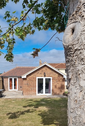 A brick house with a tiled roof, a front door, and a large window. - Home-from-home new-build bungalow in the heart of the Isle of Wight (Ryde)