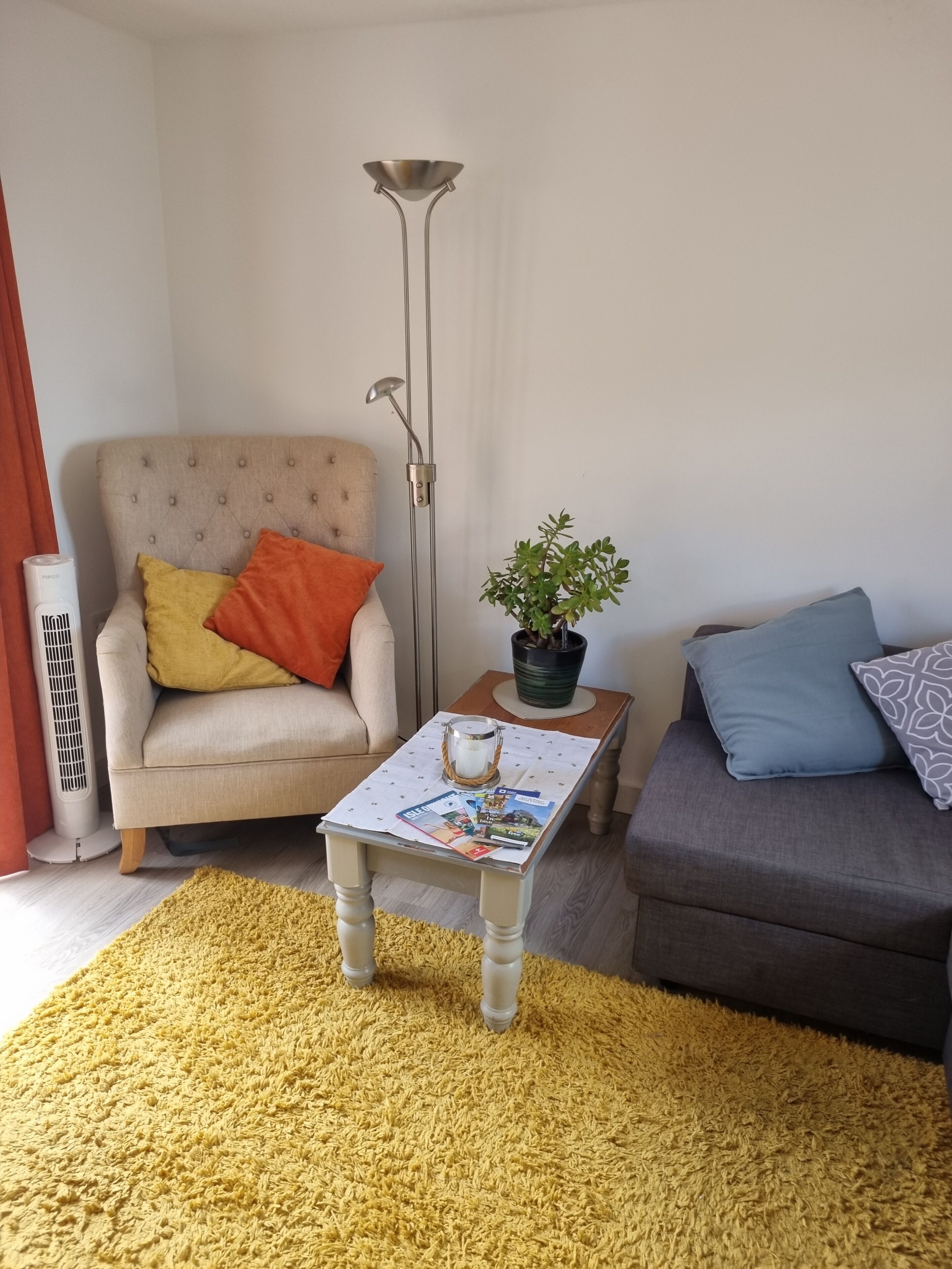 Una sala de estar con sofá, sillón, mesa de centro y lámpara de pie.
