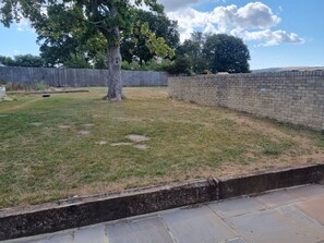Un jardin avec un arbre, un mur de briques et une bordure en pierre.